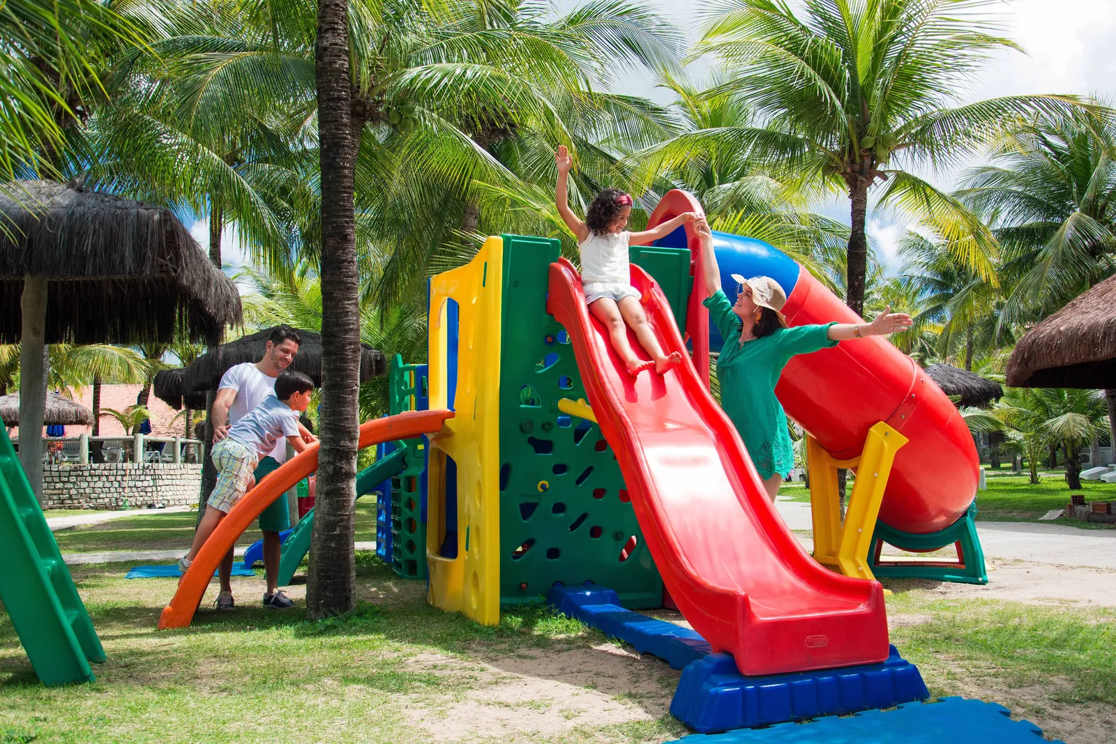Família brincando no parquinho entre coqueiros